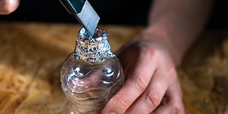 Gravity bucket bong: Remove the bottle cap and wrap tin foil around the top of the first bottle